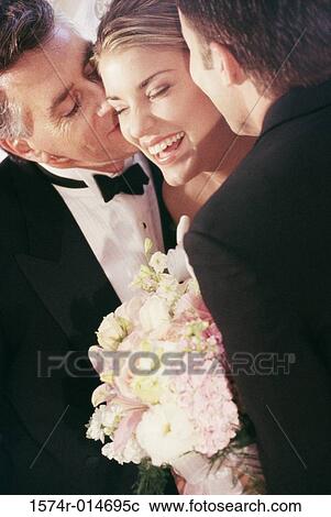 Stock Image - Father and groom kissing the bride. Fotosearch