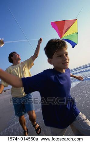 Stock Image - Father and son flying a kite on the beach. Fotosearch