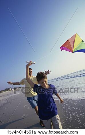 Stock Image - Father and son flying a kite on the beach. Fotosearch