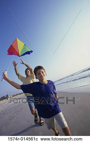 Stock Image - Father and son flying a kite on the beach. Fotosearch