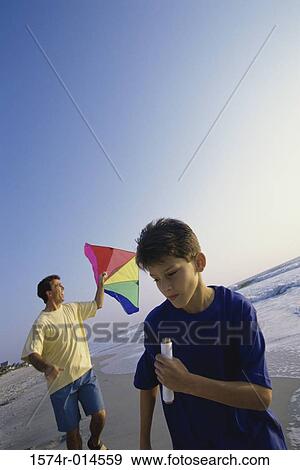 Father and son flying a kite on the beach View Large Photo Image Stock Photo - Father and son flying a kite on the beach. Fotosearch