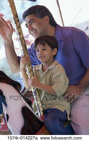 Stock Image - Father and son sitting on a carousel horse. Fotosearch
