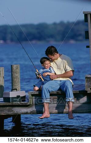 Stock Image - Father and son sitting on a pier fishing. Fotosearch
