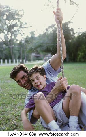 Father and son swinging on a rope swing View Large Photo Image Stock Image - Father and son swinging on a rope swing. Fotosearch