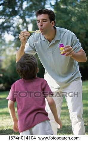 Father blowing bubbles with a bubble wand View Large Photo Image Picture - Father blowing bubbles with a bubble wand. Fotosearch