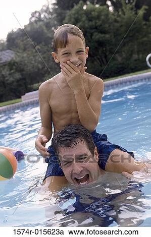 Father carrying his son in a swimming pool View Large Photo Image Stock Image - Father carrying his son in a swimming pool. Fotosearch