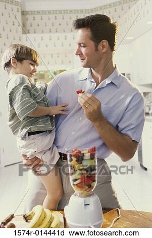 Stock Image - Father holding his son in the kitchen. Fotosearch