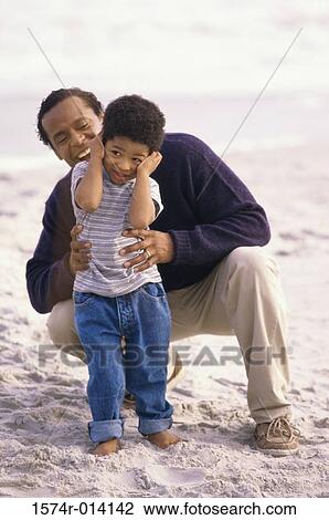 Stock Image - Father playing with his son on the beach. Fotosearch