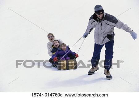 Stock Image - Father pulling his family on a sled. Fotosearch