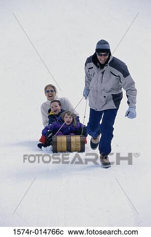 Stock Image - Father pulling his family on a sled. Fotosearch