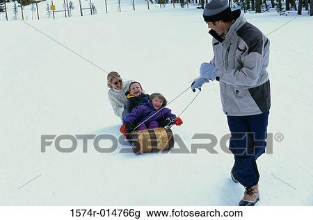Stock Image - Father pulling his family on a sled. Fotosearch