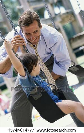 Father pushing his son on a swing View Large Photo Image Stock Photo - Father pushing his son on a swing. Fotosearch