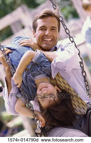 Stock Image - Father sitting on a swing with his daughter. Fotosearch