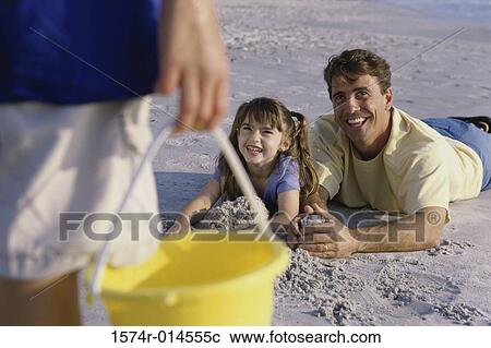Stock Image - Father with his daughter making a sand castle on the beach. Fotosearch