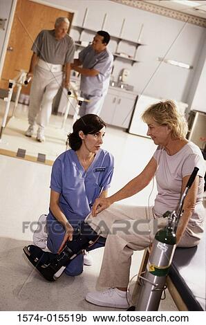 Stock Image - Female nurse adjusting a prosthesis on a patient's leg. Fotosearch