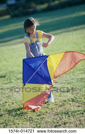 Girl holding a kite on a lawn View Large Photo Image Stock Image - Girl holding a kite on a lawn. Fotosearch