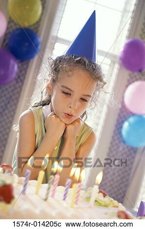 Stock Image - Girl looking at lit candles on a birthday cake. Fotosearch