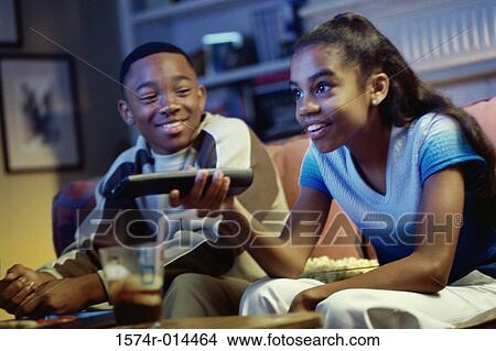 Picture - Girl watching television with her brother looking at her. Fotosearch