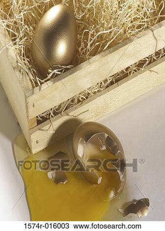 Stock Image - Golden egg in a wooden box and another broken. Fotosearch