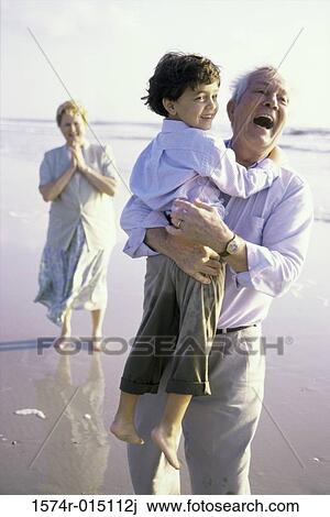 Grandfather carrying his grandson on the beach View Large Photo Image Stock Image - Grandfather carrying his grandson on the beach. Fotosearch