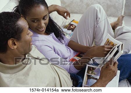 Stock Image - High angel view of a mid adult couple reading a magazine. Fotosearch