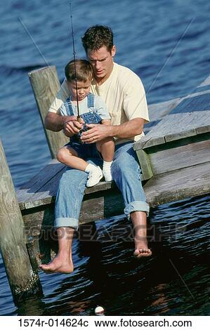 Stock Image - High angle view of a father teaching his son to fish. Fotosearch