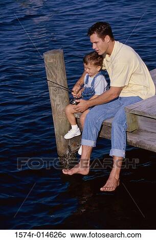 Stock Image - High angle view of a father teaching his son to fish. Fotosearch