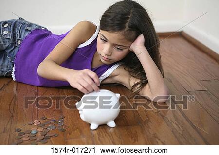 High angle view of a girl inserting coins into a piggy bank View Large Photo Image Stock Image - High angle view of a girl inserting coins into a piggy bank. Fotosearch