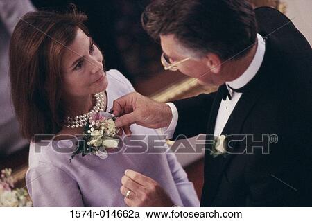 Stock Image - High angle view of a mature man adjusting the boutonniere of a mature woman. Fotosearch