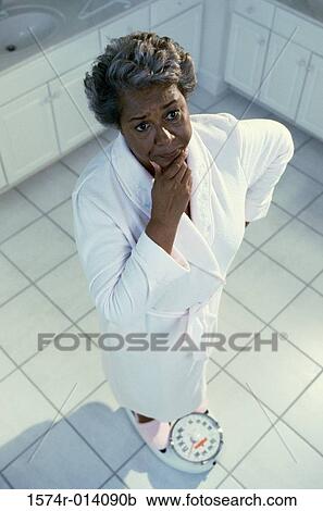 High angle view of a mature woman standing on a weight scale View Large Photo Image Stock Image - High angle view of a mature woman standing on a weight scale. Fotosearch
