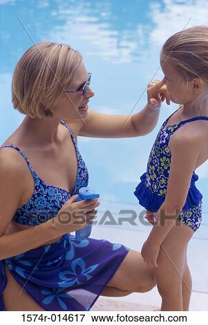 Stock Photo - High angle view of a mother applying suntan lotion on her daughter. Fotosearch