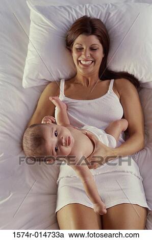 High angle view of a mother lying in bed playing with her son View Large Photo Image Stock Image - High angle view of a mother lying in bed playing with her son. Fotosearch