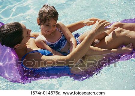 Stock Image - High angle view of a mother with her daughter on a pool raft in a swimming pool. Fotosearch