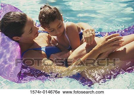 Stock Image - High angle view of a mother with her daughter on a pool raft in a swimming pool. Fotosearch