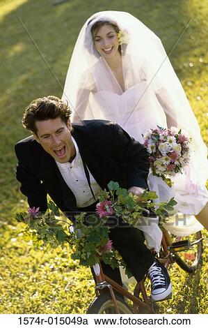 High angle view of a newlywed couple riding a bicycle View Large Photo Image Stock Image - High angle view of a newlywed couple riding a bicycle. Fotosearch