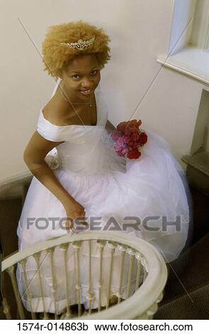 Stock Image - High angle view of a newlywed woman walking up stairs. Fotosearch