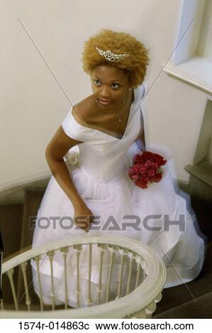 Stock Image - High angle view of a newlywed woman walking up stairs. Fotosearch