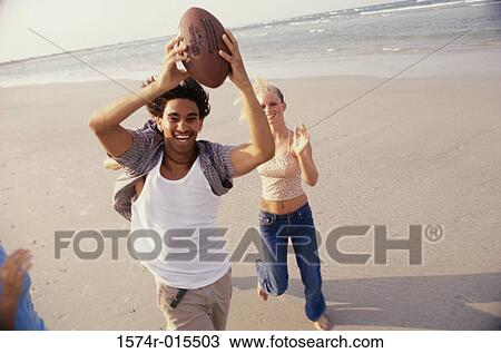 High angle view of a teenage couple playing football on the beach View Large Photo Image Stock Image - High angle view of a teenage couple playing football on the beach. Fotosearch
