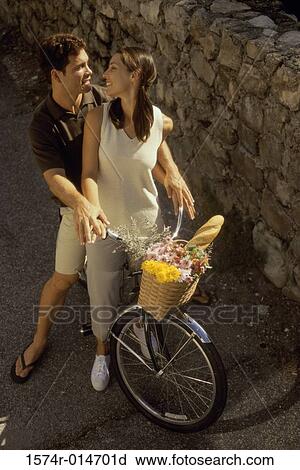 High angle view of a young couple sitting on a bicycle View Large Photo Image Stock Image - High angle view of a young couple sitting on a bicycle. Fotosearch