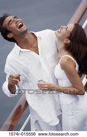 Stock Photograph - High angle view of a young couple standing on the deck of a cruise ship and laughing. Fotosearch