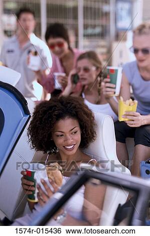 High angle view of a young woman eating food with her friends in a car View Large Photo Image Stock Photograph - High angle view of a young woman eating food with her friends in a car. Fotosearch