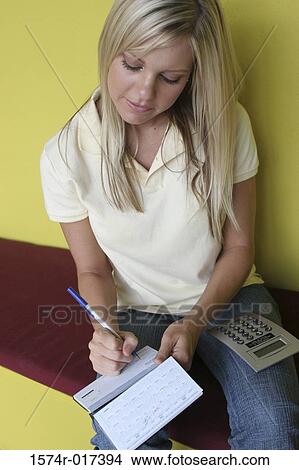 High angle view of a young woman writing a check View Large Photo Image Picture - High angle view of a young woman writing a check. Fotosearch
