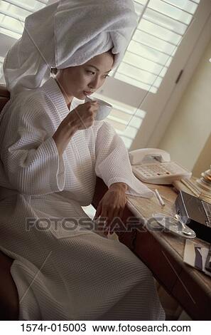 Stock Image - High angle view of a young woman drinking a cup of coffee. Fotosearch