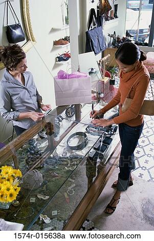 Stock Image - High angle view of a young woman standing at a checkout counter in a store. Fotosearch