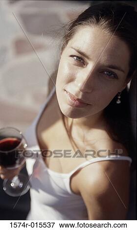 Stock Photo - High angle view of a young woman holding a glass of wine. Fotosearch