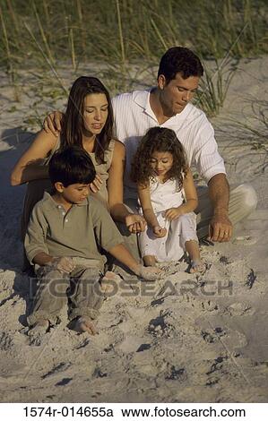 High angle view of parents and their two children sitting on the beach View Large Photo Image Stock Image - High angle view of parents and their two children sitting on the beach. Fotosearch