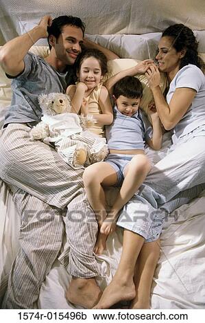 High angle view of parents lying on a bed with their son and daughter View Large Photo Image Stock Image - High angle view of parents lying on a bed with their son and daughter. Fotosearch