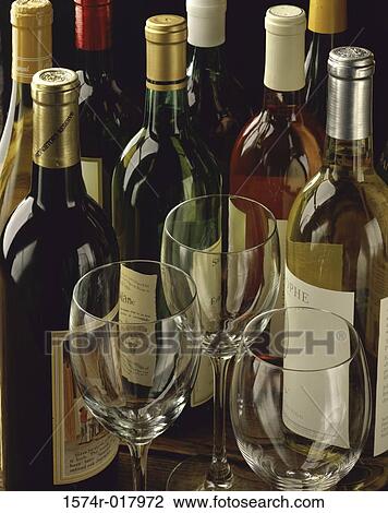 Stock Image - High angle view of three wineglasses with wine bottles in the background. Fotosearch
