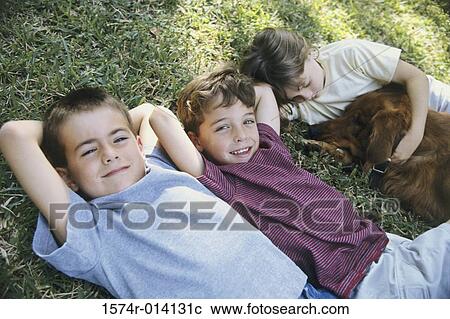 High angle view of two boys and a girl lying on the grass with a dog View Large Photo Image Stock Image - High angle view of two boys and a girl lying on the grass with a dog. Fotosearch