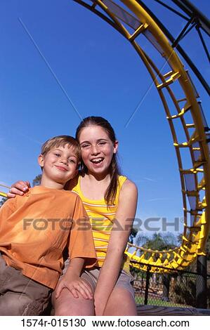 Low angle view of a boy and girl smiling near a rollercoaster View Large Photo Image Stock Image - Low angle view of a boy and girl smiling near a rollercoaster. Fotosearch